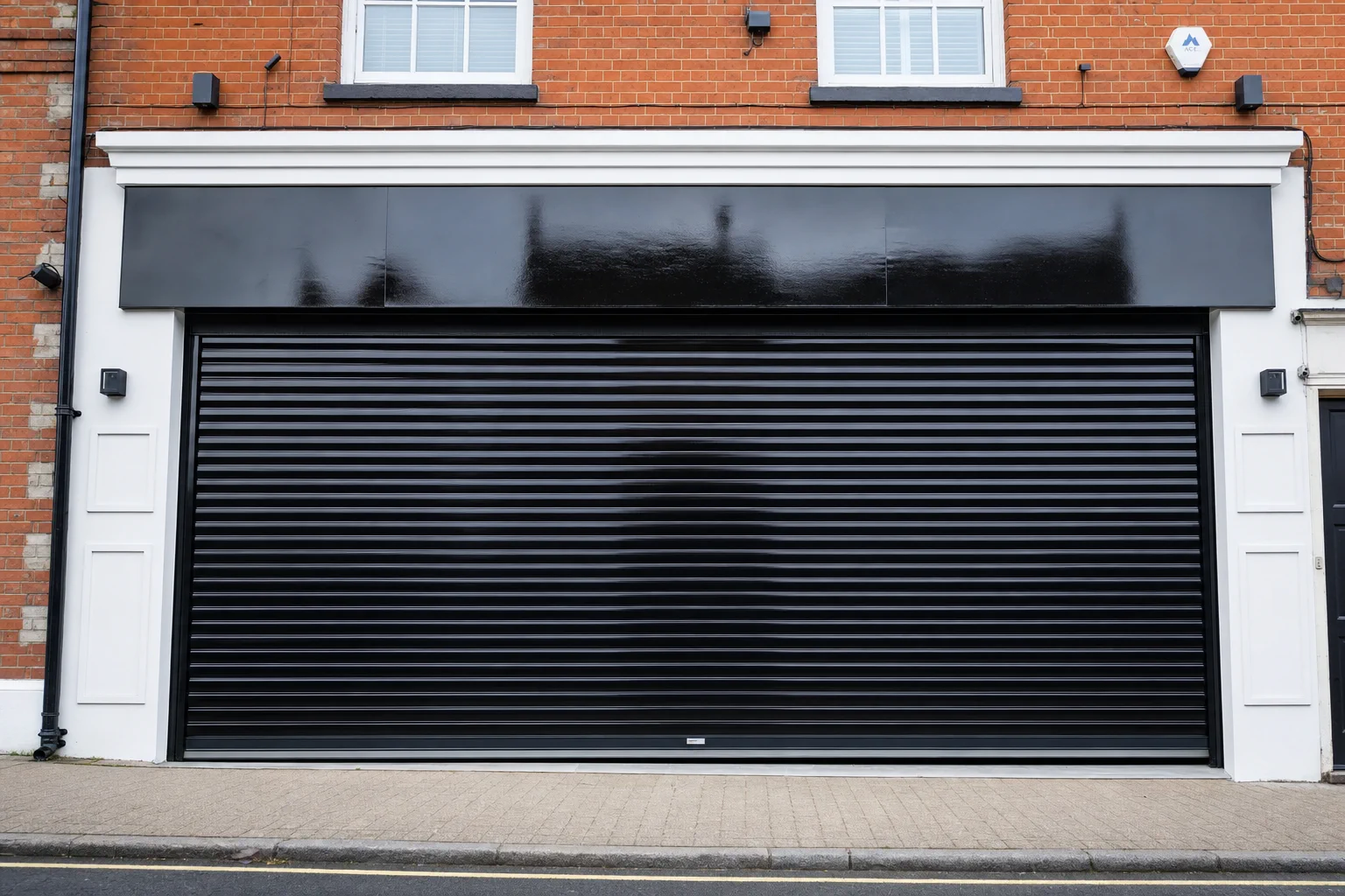 Jay on a ladder spraying a commercial roller shutter navy blue on a UK high street